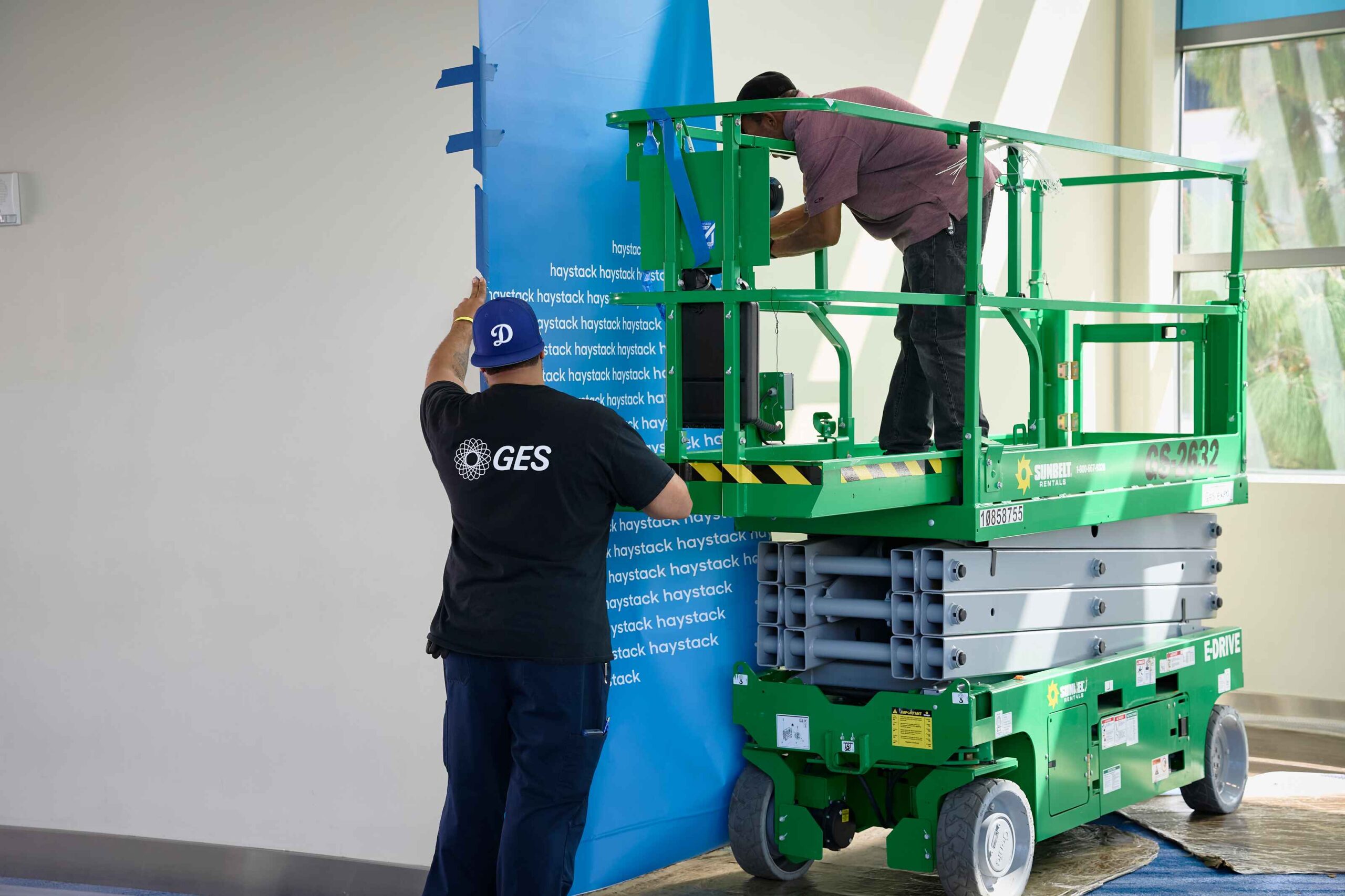 GES team working on trade show graphic on-site on a lift.
